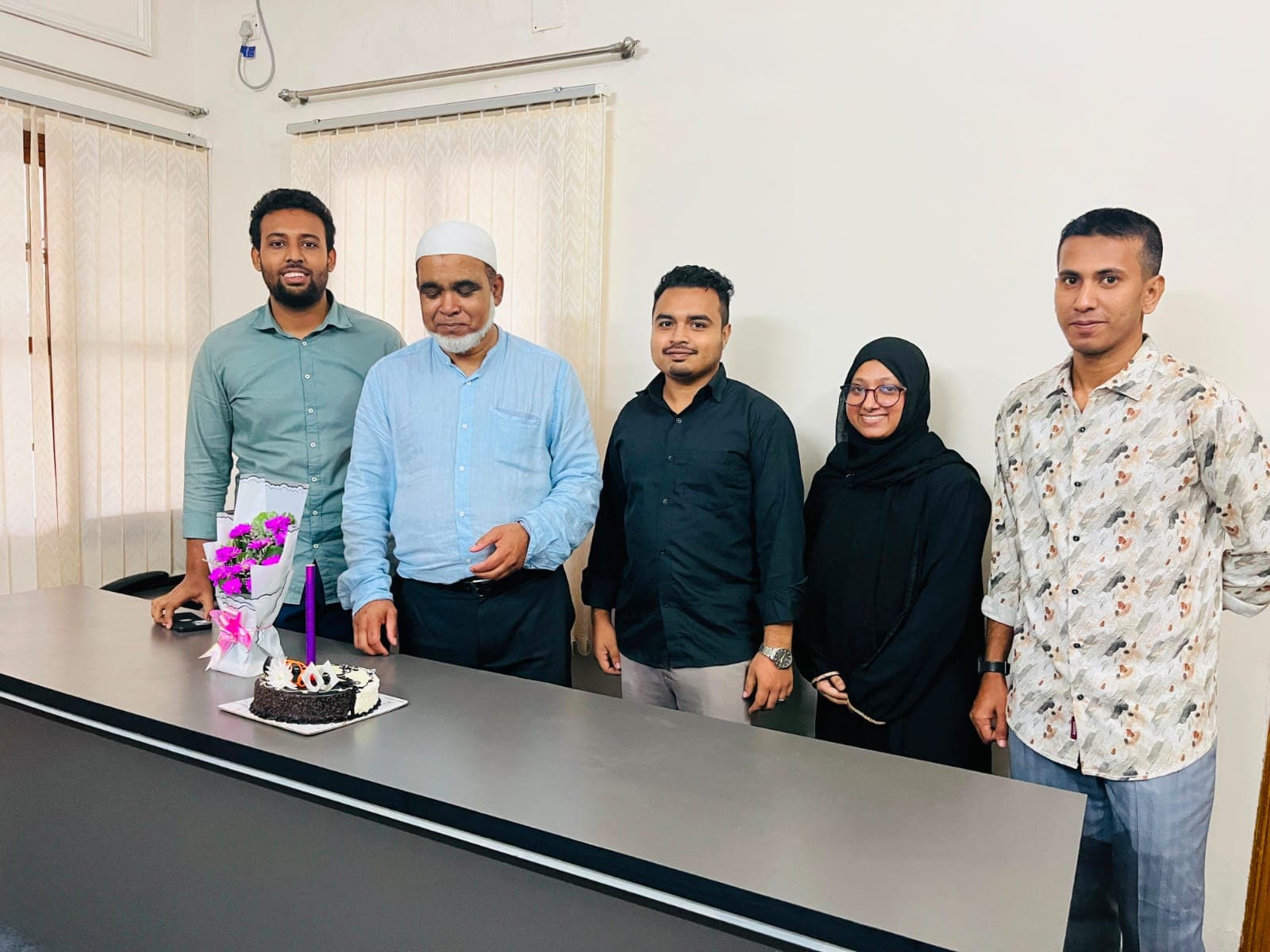 Tareq Mahmud standing with four colleagues at a desk in the office